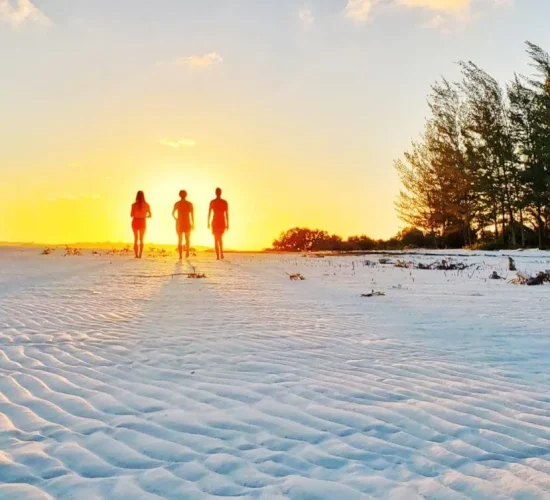 Guests walking on rippled white sand at sunset in Balabac